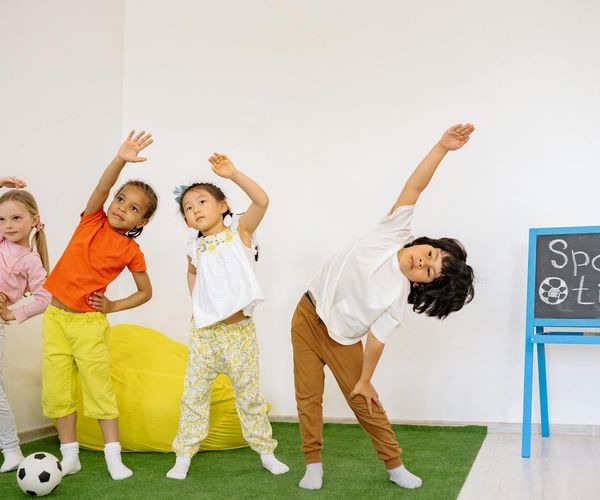 Happy child in a tree yoga pose in a colorful room.